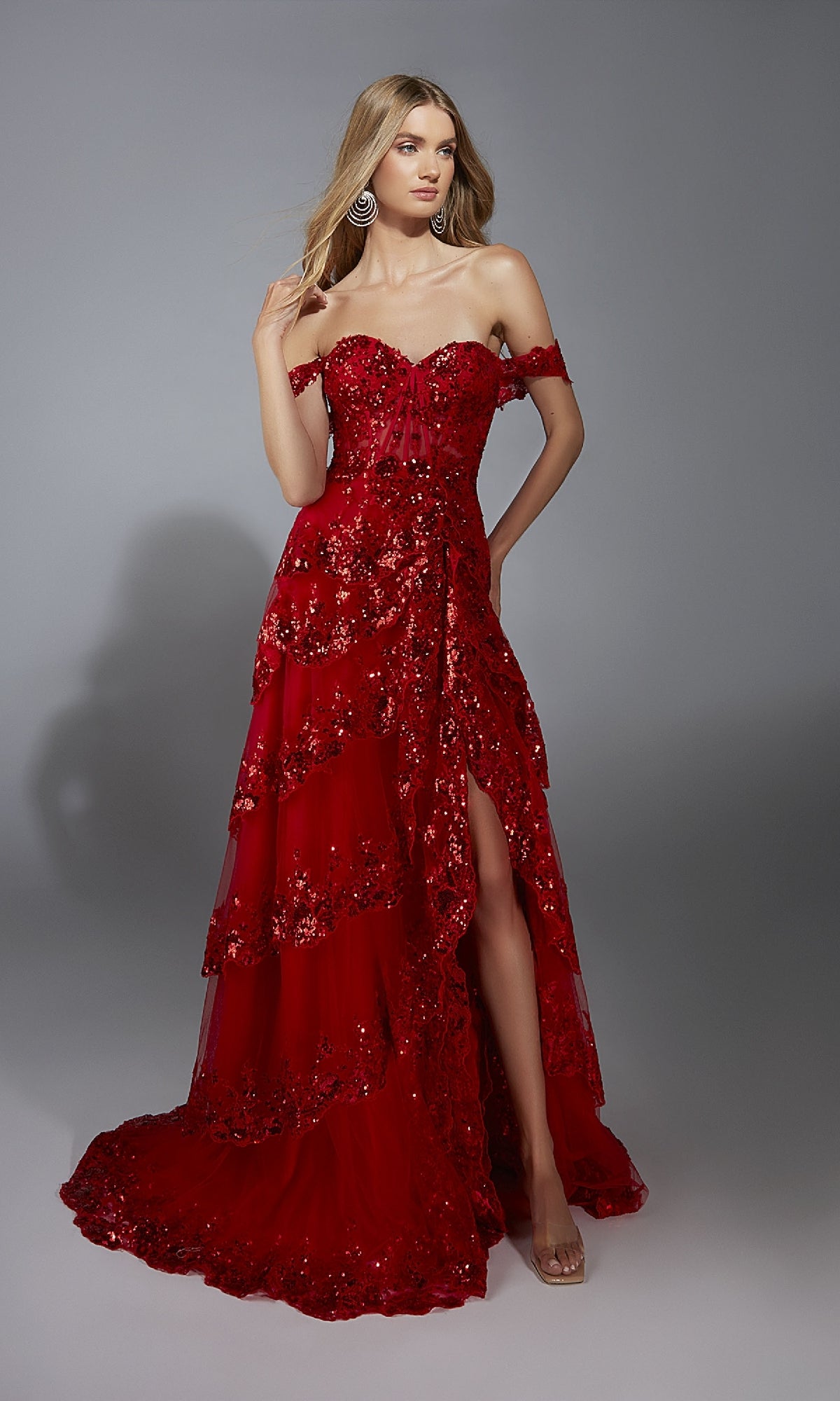 Woman wearing the Aerie Couture 333 long prom dress, featuring a strapless off-the-shoulder design, corset bodice, sequin details, and thigh-high slit, poses against a plain gray background.